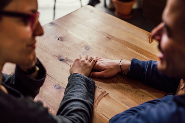 Man and woman sitting together, talking and holding hands