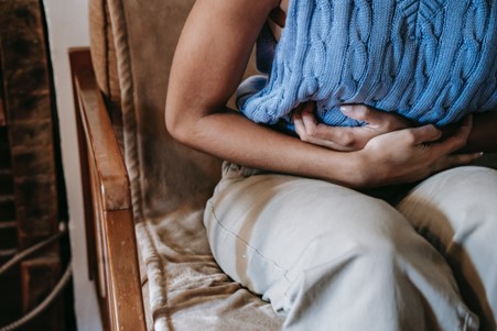 a person holding their stomach showing the link between anxiety and your gut health