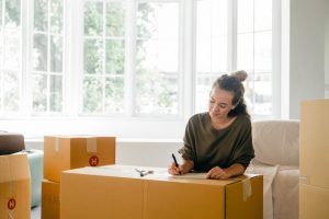 Woman writing on a cardboard box while packing for a move