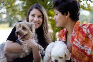 Two women smiling while holding their dogs.