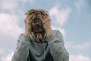 A man putting his hands on his head while looking down