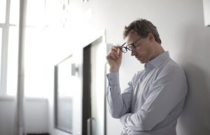 A stressed man taking off his glasses