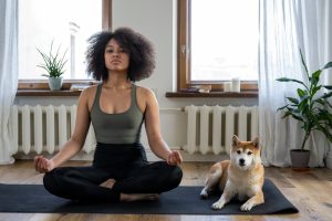 Woman doing yoga next to her dog.