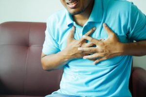 A man in a blue shirt putting his hands on his chest